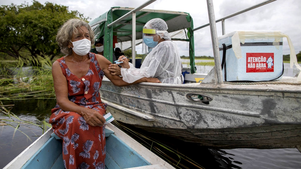 Profissional da saúde vacina Olga Pimentel, de 72 anos, nas margens do Rio Negro. 2021. Foto de Michael Dantas. Acervo pessoal.