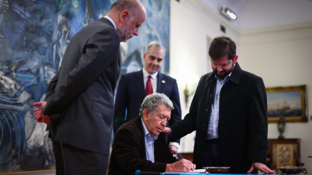 Evandro Teixeira autografa o catálogo da exposição para o presidente do Chile, Gabriel Boric, à direita na foto. No centro, o embaixador do Brasil, Paulo Pacheco, e à esquerda, o secretário da presidência do Chile, Álvaro Elizalde.