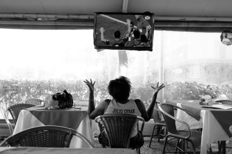 Sem título #10, 2014, da série Offside Brazil. 30 x 42 cm. © David Alan Harvey/ Magnum Photos. Coleção de Arte Contemporânea/ Acervo IMS  Woman watching the Brazilian match being repeated in a restaurant in Copacabana.