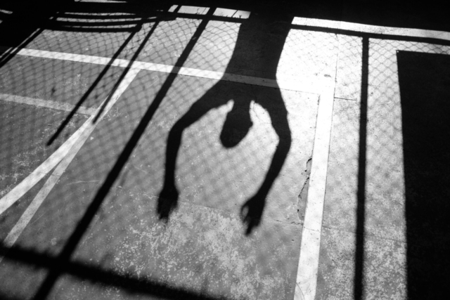 Sem título #8, 2014, da série Offside Brazil. 30 x 42 cm. © David Alan Harvey/ Magnum Photos. Coleção de Arte Contemporânea/ Acervo IMS [Spectator hangs on a chain link fence watching an indoor football game in Morro dos Prazeres, in Rio de Janeiro]