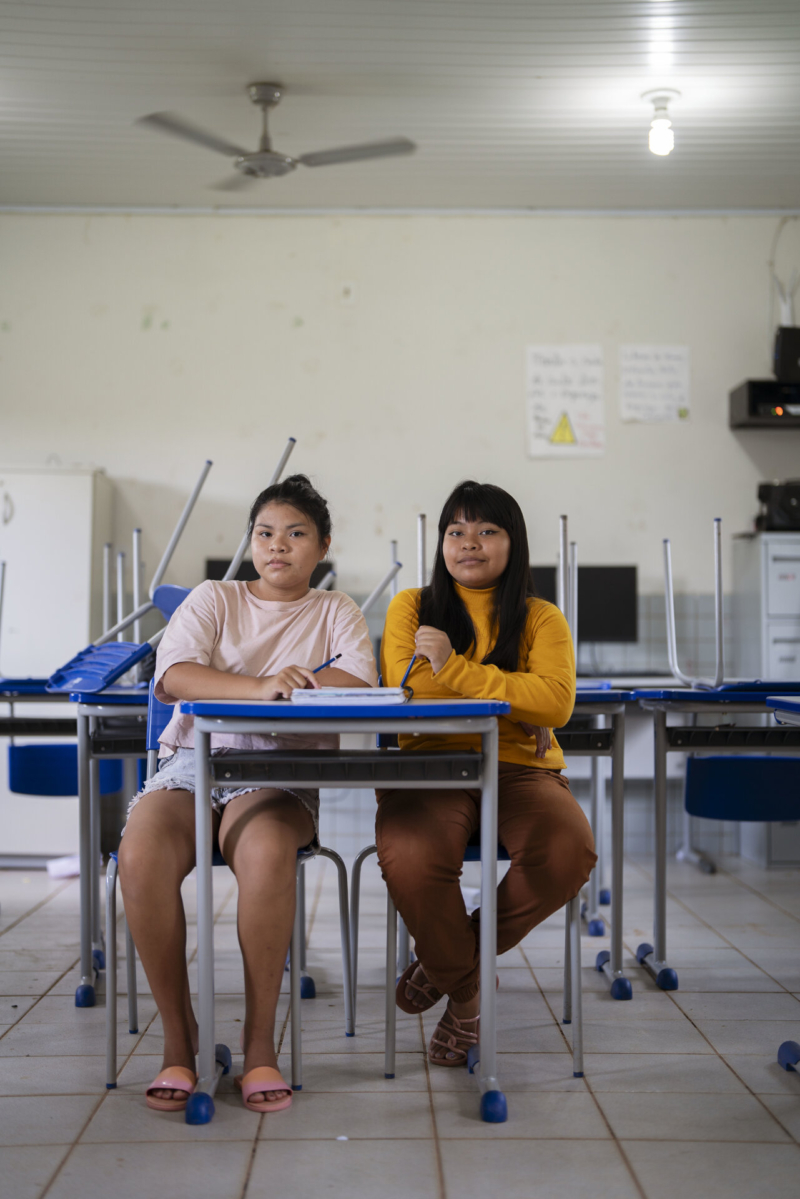 Sthefany Suru&iacute; e Kaylane Suru&iacute;, Aldeia Lapetanha, 2024.  Temos, hoje, escolas em nossas aldeias onde crian&ccedil;as e jovens aprendem as disciplinas regulares oferecidas pela educa&ccedil;&atilde;o p&uacute;blica. No entanto, o que nos distingue &eacute; a exist&ecirc;ncia de uma disciplina de l&iacute;ngua materna, atrav&eacute;s da qual o professor ind&iacute;gena ensina sobre a riqueza dos conhecimentos ancestrais do nosso povo. Com o intuito de fortalecer esse aprendizado, v&aacute;rios anci&atilde;os da aldeia s&atilde;o convidados para auxiliar na condu&ccedil;&atilde;o das aulas, transmitindo sabedoria de gera&ccedil;&atilde;o para gera&ccedil;&atilde;o. Foto de Coletivo Lakapoy.  (Legenda por Coletivo Lakapoy).  Fotografias em pigmento mineral sobre papel de algod&atilde;o impressas em 2025. 66 x 98 cm. Cole&ccedil;&atilde;o de Arte Contempor&acirc;nea / Acervo IMS 