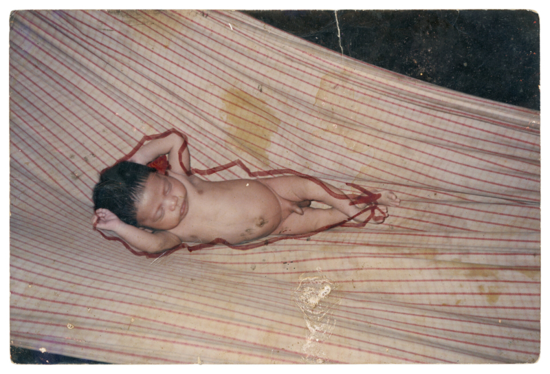 Manass&eacute;s Suru&iacute;, Aldeia Lapetanha, c. 1993 Muitas vezes, quando minha m&atilde;e n&atilde;o estava por perto, eu, Manass&eacute;s, e meus irm&atilde;os e primos nos reun&iacute;amos para olhar as fotos da fam&iacute;lia. Naquela &eacute;poca, as fotografias n&atilde;o tinham a mesma import&acirc;ncia que damos hoje, ent&atilde;o costum&aacute;vamos rabisc&aacute;-las com canetinhas. Faz&iacute;amos contornos das pessoas nas fotos, desenh&aacute;vamos barbas e bigodes nos rostos. Embora essas lembran&ccedil;as tragam um certo carinho, esta foto que o Almir tirou me remete a um tempo em que nossa fam&iacute;lia n&atilde;o tinha condi&ccedil;&otilde;es financeiras para comprar uma rede de dormir, nem mesmo roupas para os beb&ecirc;s. Nossas necessidades mudaram ap&oacute;s o contato com os brancos e, como n&atilde;o era da nossa cultura, levamos muitos anos para tentar nos adaptar a elas. Com isso, recordamos essa fase dif&iacute;cil de nossas vidas. Hoje, j&aacute; adultos, trabalhamos com a produ&ccedil;&atilde;o de caf&eacute;, banana, castanha e outros produtos, buscando gerar renda e proporcionar uma melhor qualidade de vida para nossa fam&iacute;lia. Foto de Almir Suru&iacute;. (Legenda por Coletivo Lakapoy).  Fotografias em pigmento mineral sobre papel de algod&atilde;o impressas em 2025. 92 x 63,2 cm. Cole&ccedil;&atilde;o de Arte Contempor&acirc;nea / Acervo IMS 