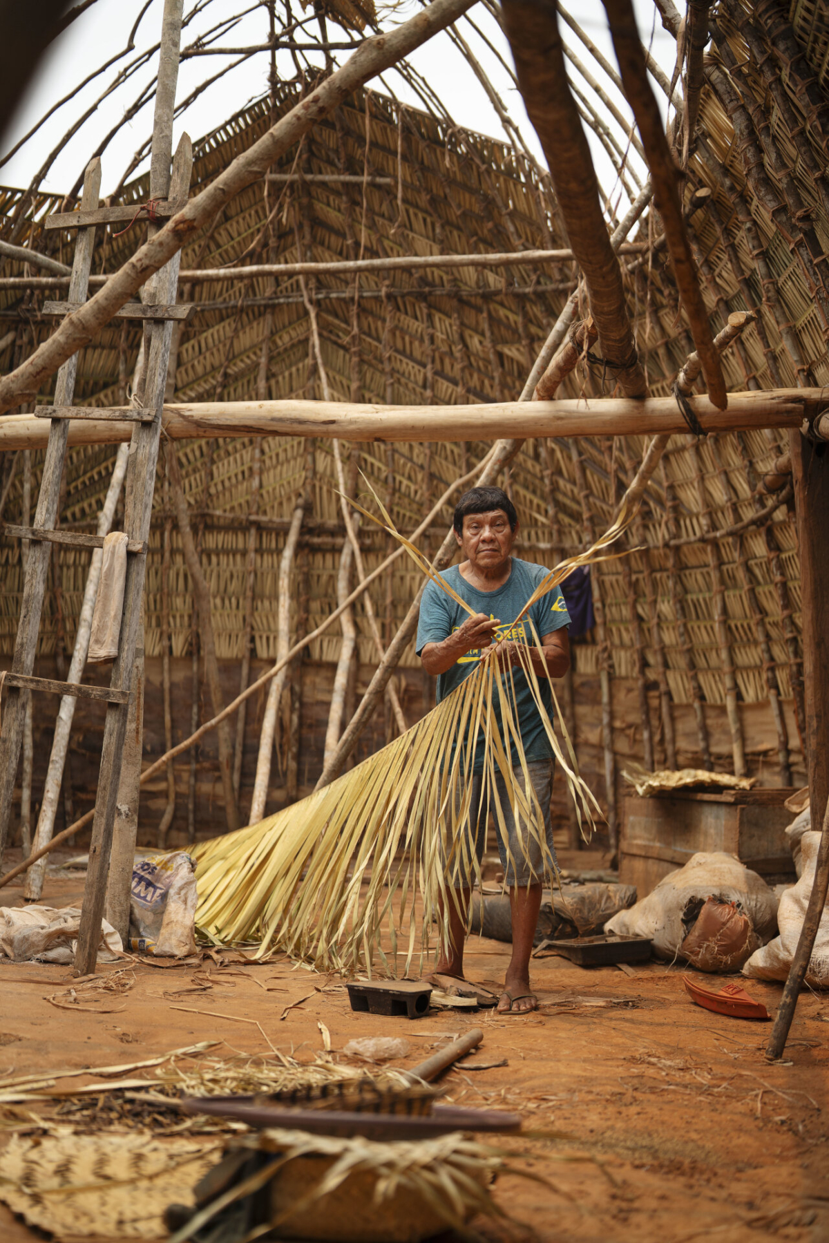 Agamenon Suru&iacute;, Aldeia Lapetanha, 2024 A maloca tradicional de Agamenon ficou muito velha ap&oacute;s 5 anos. Ele ent&atilde;o convidou todos os filhos homens para derrubar a casa velha e construir uma nova maloca no mesmo local. Toda a estrutura da casa &eacute; constru&iacute;da da forma tradicional, usando cip&oacute;s, casca de madeiras, palhas de baba&ccedil;u e outros materiais da floresta. Foto de Coletivo Lakapoy. (Legenda por Coletivo Lakapoy).  Fotografias em pigmento mineral sobre papel de algod&atilde;o impressas em 2025. 66 x 98 cm. Cole&ccedil;&atilde;o de Arte Contempor&acirc;nea / Acervo IMS  