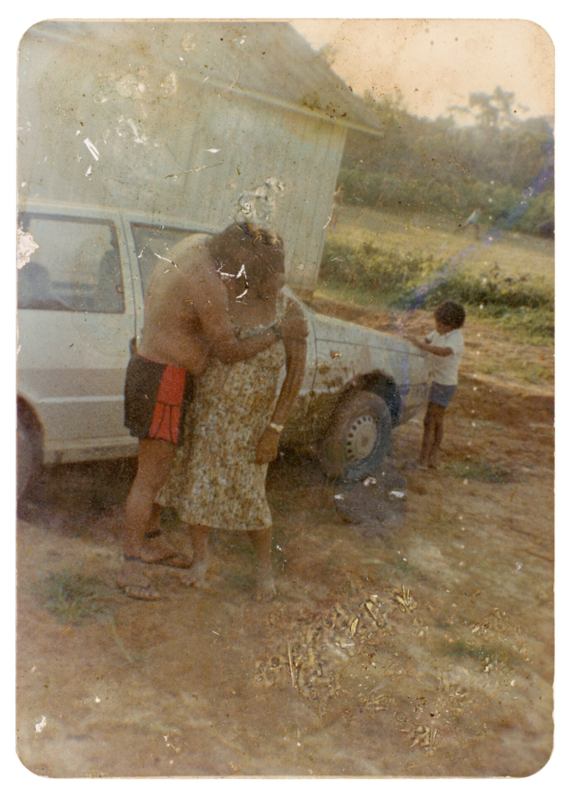 7 - Itabira Suru&iacute; e Sandra Suru&iacute; e crian&ccedil;a Paiter Suru&iacute; Aldeia Lapetanha, anos 1990 A conviv&ecirc;ncia com os brancos introduziu novos costumes e valores no territ&oacute;rio Paiter Suru&iacute;. Nesta foto, Itabira havia decidido expressar seu amor por Sandra com um beijo na boca da esposa. A demonstra&ccedil;&atilde;o, por&eacute;m, foi motivo de gargalhadas para os ind&iacute;genas presentes, j&aacute; que o ato do casal tocando os l&aacute;bios n&atilde;o existia na cultura Paiter, ou seja, n&atilde;o havia beijo na boca antes do contato com os n&atilde;o ind&iacute;genas. Autoria desconhecida. (Legenda por Coletivo Lakapoy).  Fotografias em pigmento mineral sobre papel de algod&atilde;o impressas em 2025. 52 x 71,5 cm. Cole&ccedil;&atilde;o de Arte Contempor&acirc;nea / Acervo IMS   